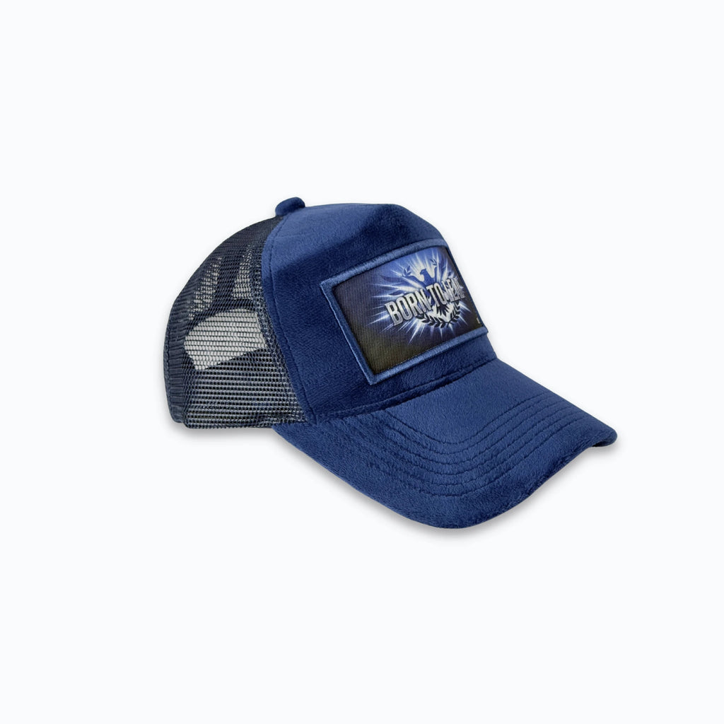 Profilbild av mörkblå velvet truckerkeps med matchande nätbaksida. Premium keps med tryck för en stark streetwear-look.
