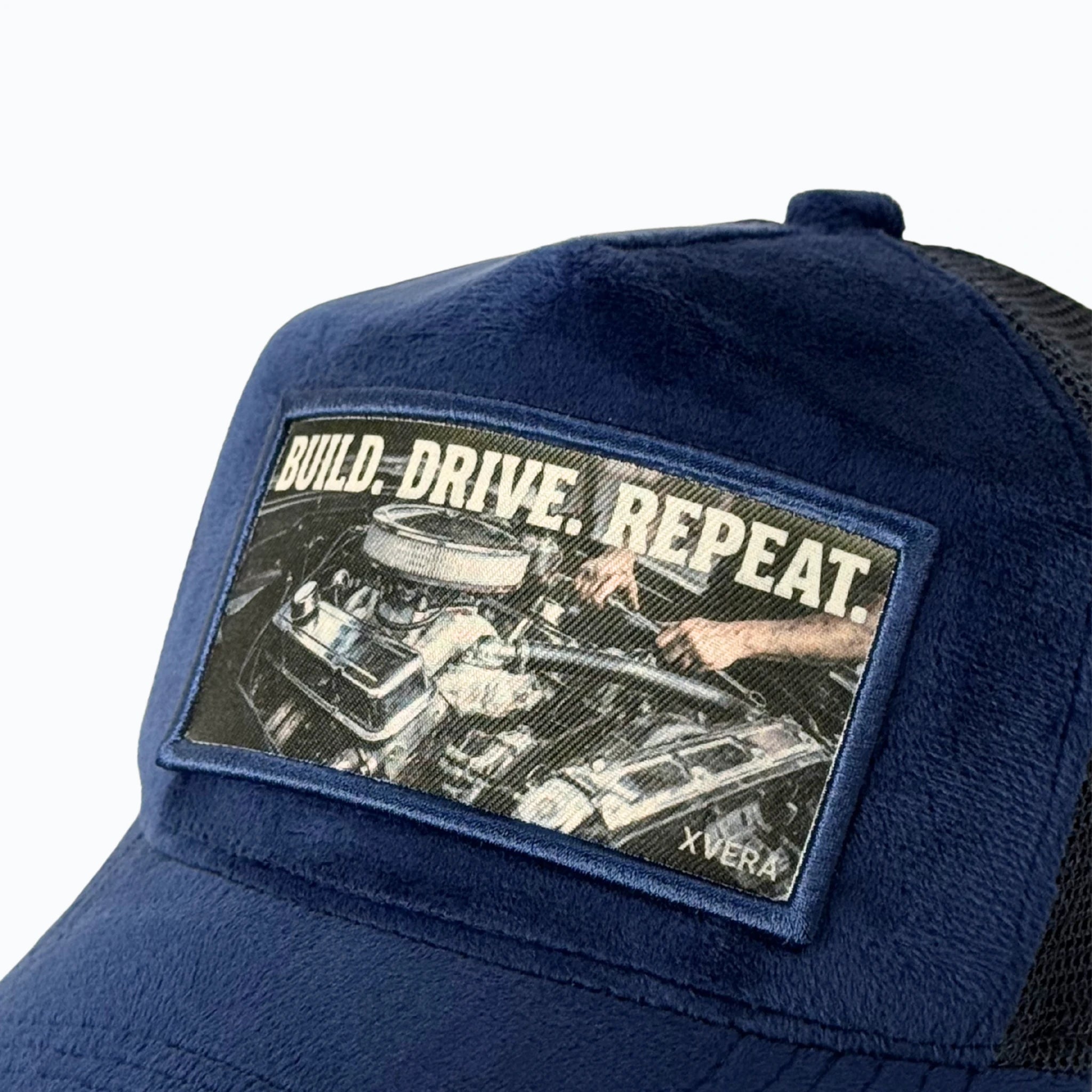 Närbild på det skarpa vita trycket BUILD DRIVE REPEAT och det exklusiva mörkblå sammetsmaterialet från XVERA.