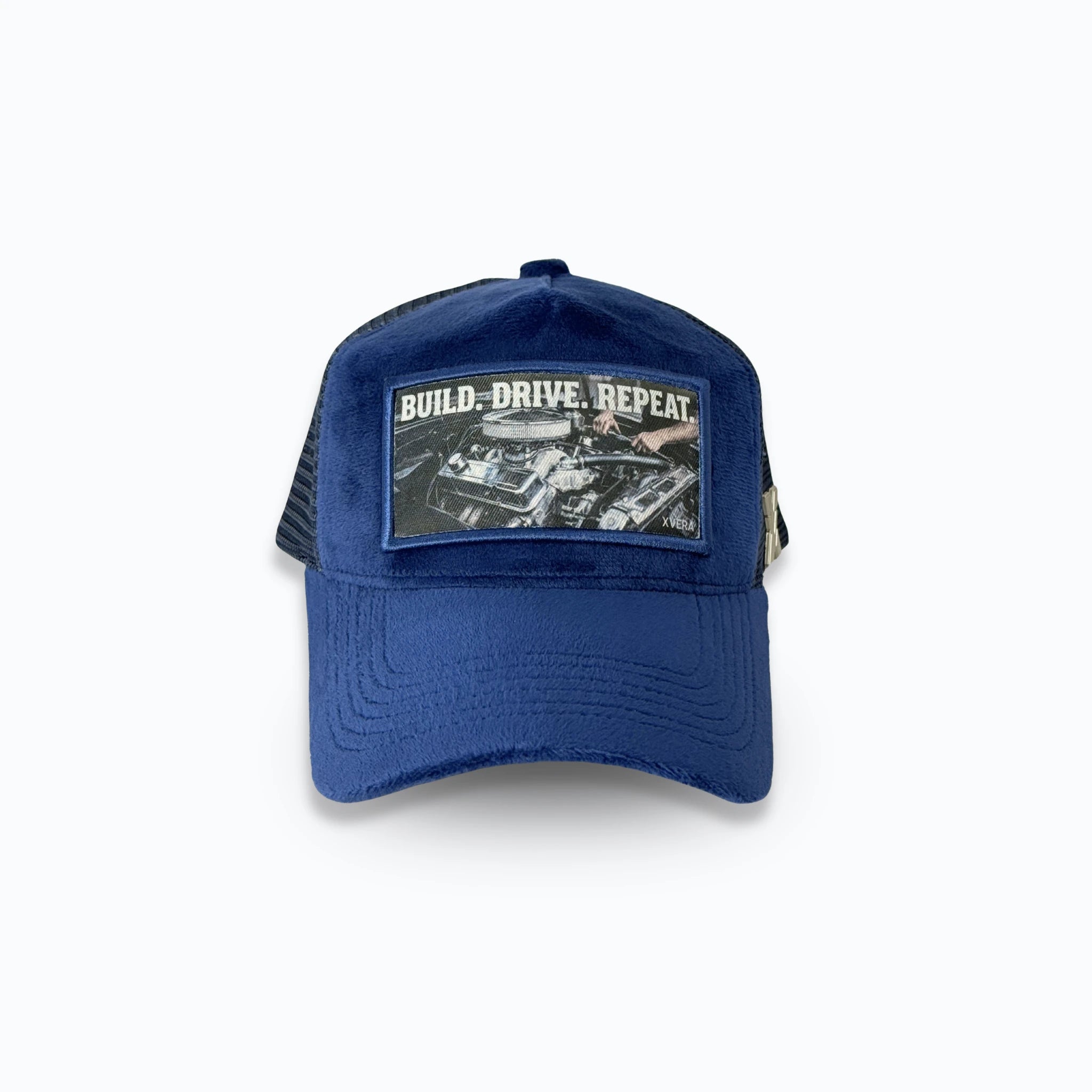 Mörkblå velvet keps framifrån med det vita trycket BUILD DRIVE REPEAT och bilmotiv. Exklusiv truckerkeps för motorintresserade från varumärket XVERA.