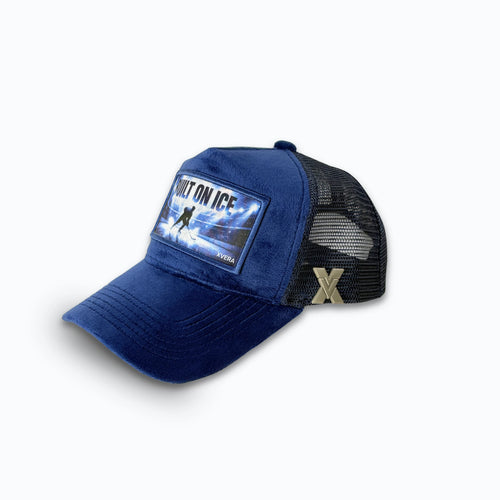 Mörkblå keps i sammet från sidan, som visar nätbaksidan och BUILT ON ICE hockeytrycket. Unisex truckerkeps från XVERA .