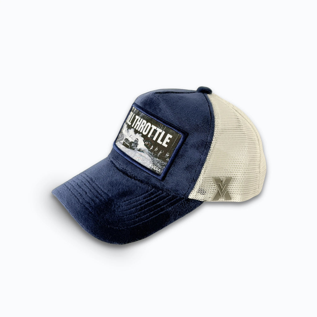 Marinblå keps i sammet från sidan, som visar den cremefärgade nätbaksidan och FULL THROTTLE rallytrycket. Unisex truckerkeps från XVERA.
