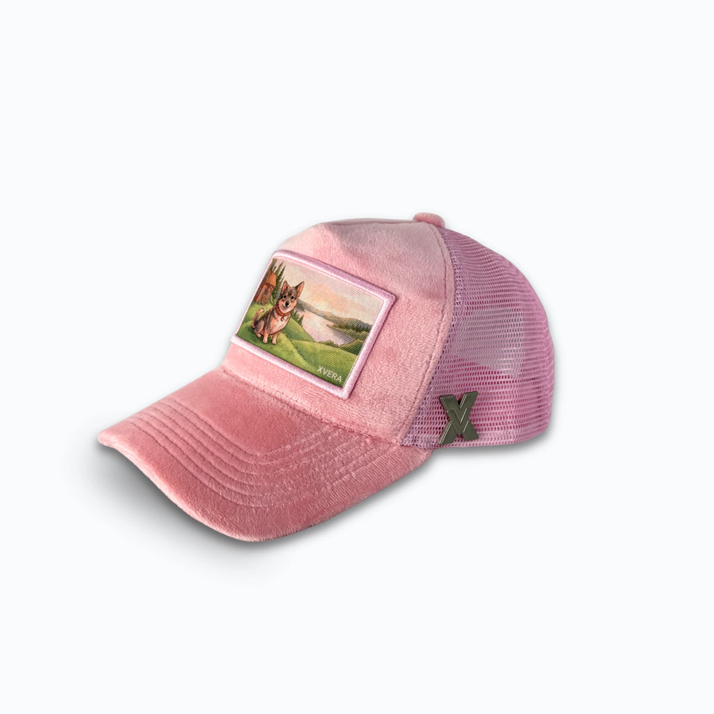 Rosa keps i sammet från sidan, som visar passformen och naturmotivet med hund och röd stuga. Unisex truckerkeps från XVERA.