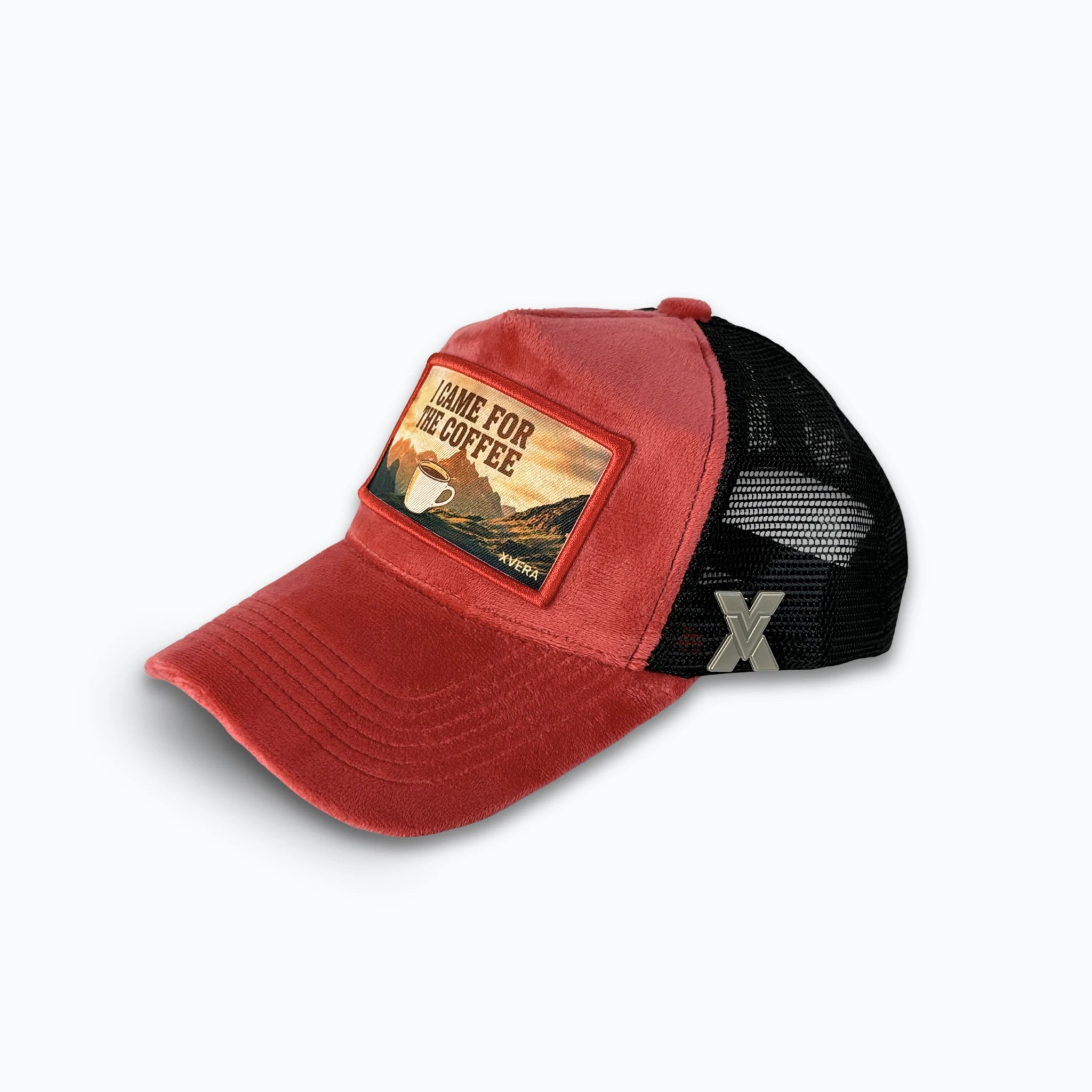 Röd keps i sammet från sidan, som visar den svarta nätbaksidan och kaffemotivet i bergen. Unisex truckerkeps från XVERA.