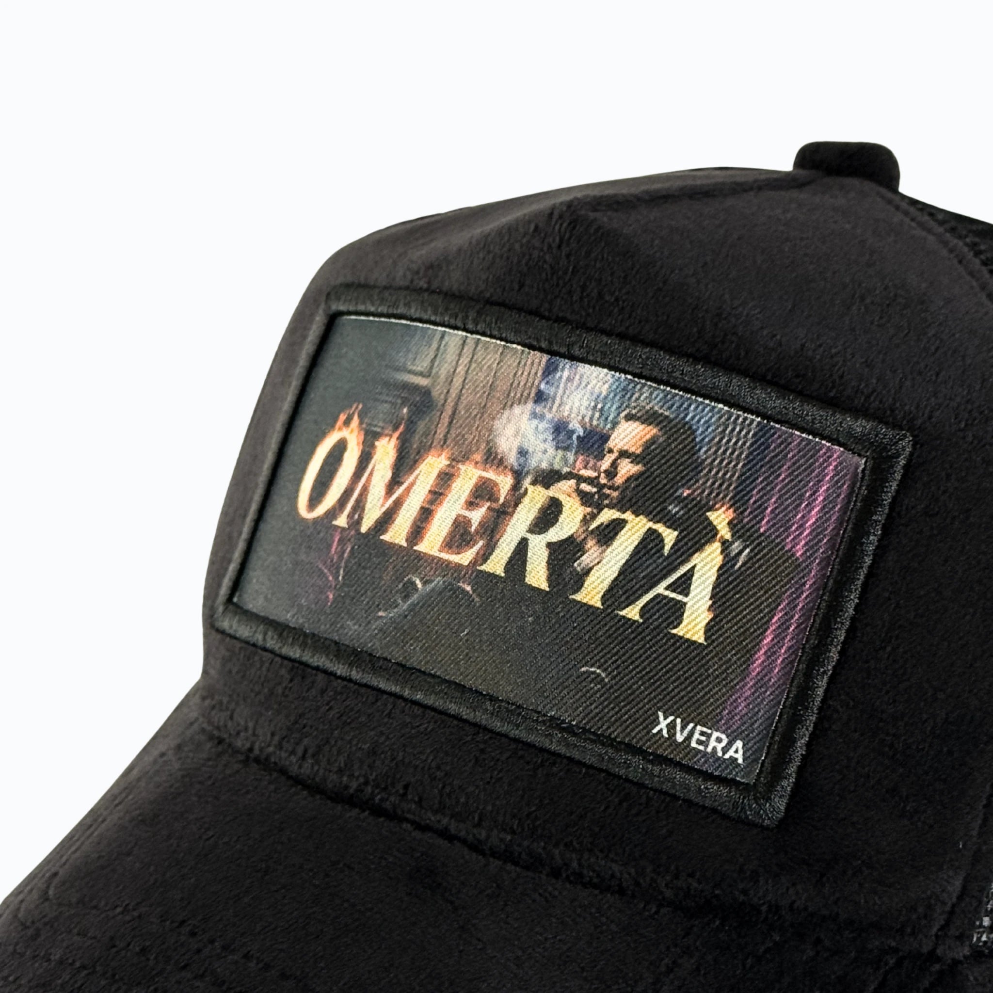 Närbild på det detaljerade trycket OMERTÀ och det exklusiva svarta sammetsmaterialet från XVERA.