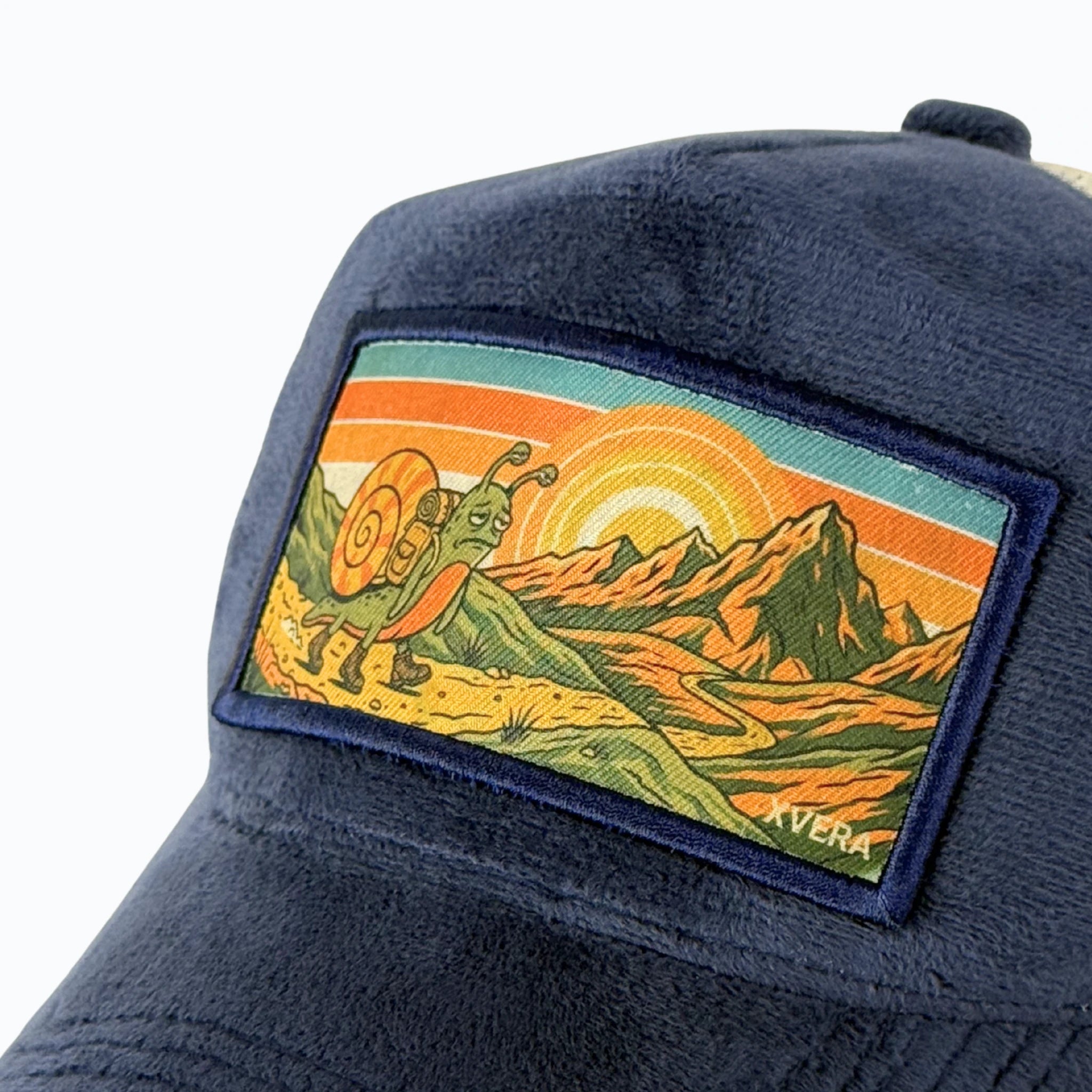 Närbild på det detaljerade retro-trycket med en vandrande snigel i ett soligt bergslandskap och det exklusiva marinblå sammetsmaterialet från XVERA.