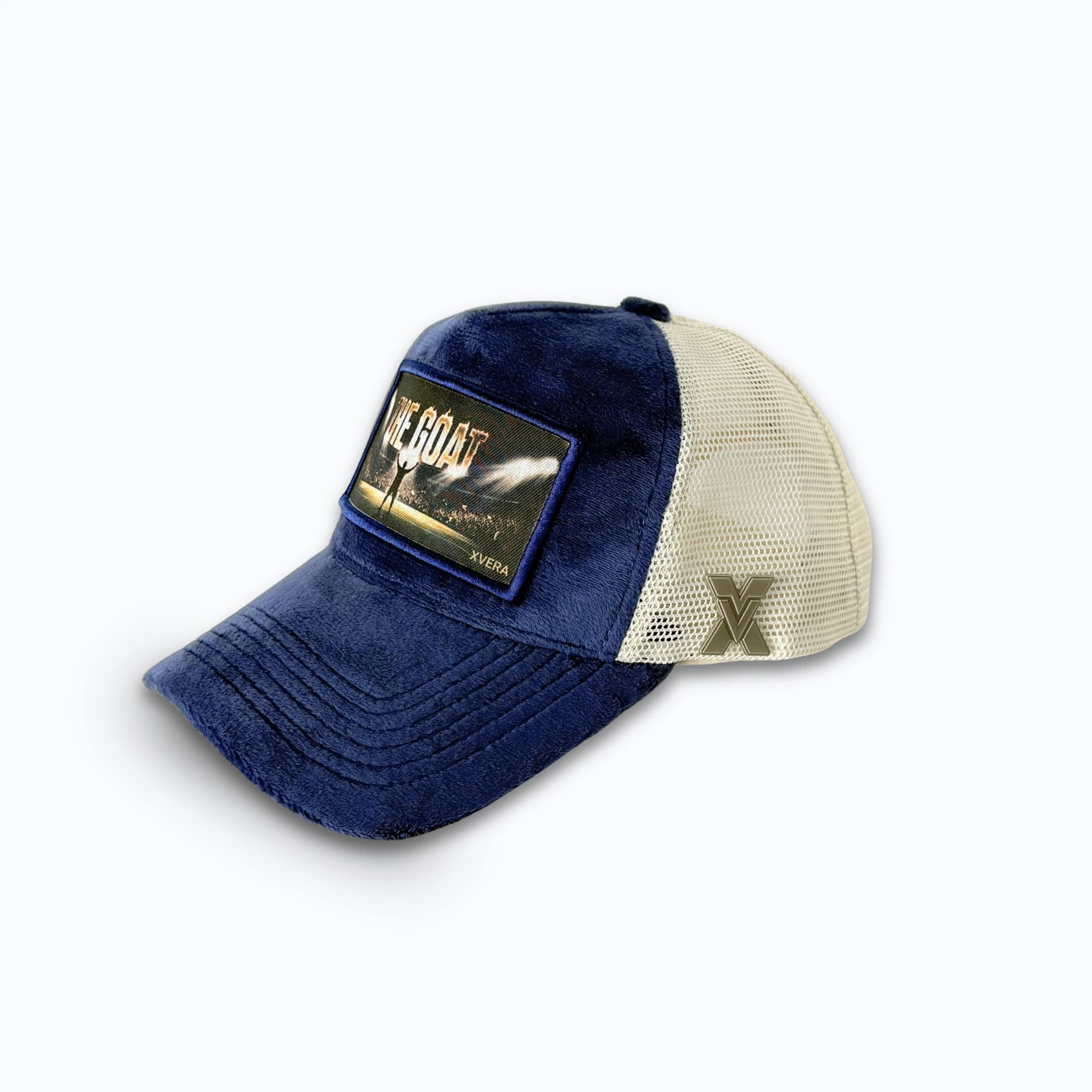 Marinblå keps i sammet från sidan, som visar den cremefärgade nätbaksidan och THE GOAT-trycket. Unisex truckerkeps från XVERA.