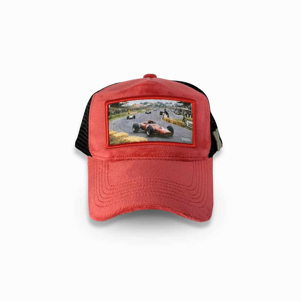 Röd velvet keps framifrån med ett vintage racingmotiv av en klassisk röd formel 1-bil på en racerbana. Exklusiv truckerkeps med bilmotiv från varumärket XVERA.