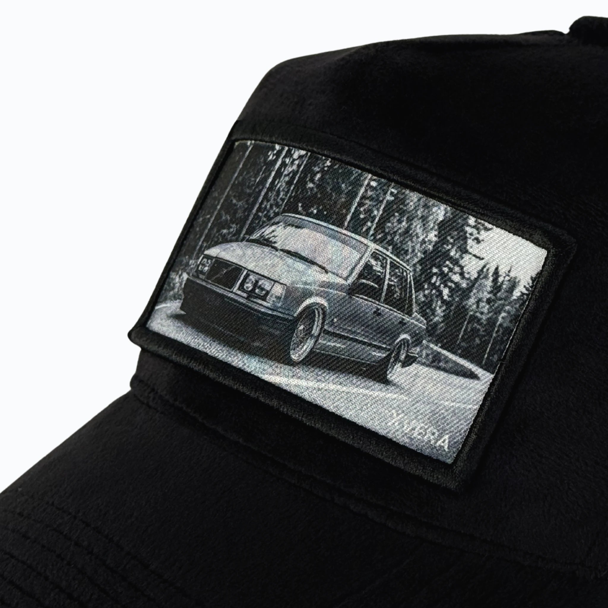 Närbild på det detaljerade trycket av en stylad Volvo på en skogsväg och det exklusiva svarta sammetsmaterialet från XVERA.