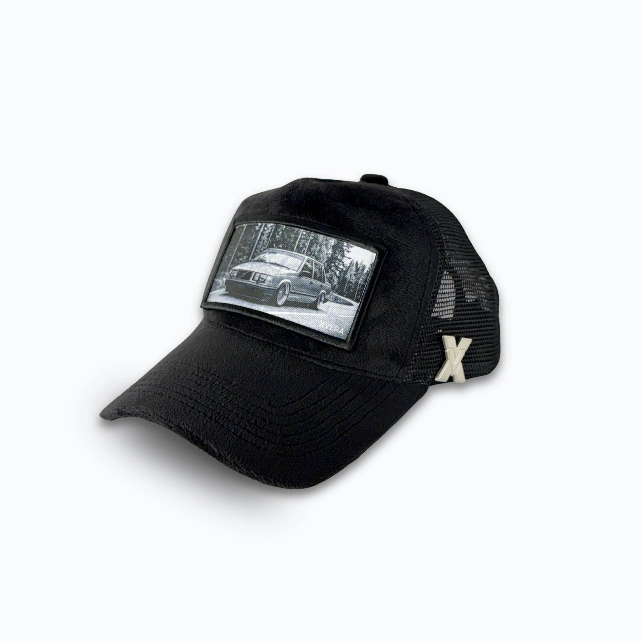 Svart keps i sammet från sidan, som visar den svarta nätbaksidan och det klassiska bilmotivet. Unisex truckerkeps från XVERA.