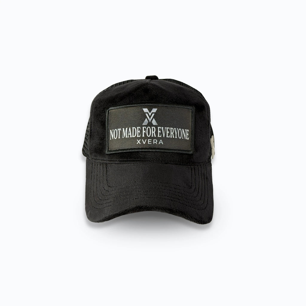 Svart velvet keps framifrån med en stilren patch och den vita texten NOT MADE FOR EVERYONE. Exklusiv statement truckerkeps från varumärket XVERA.