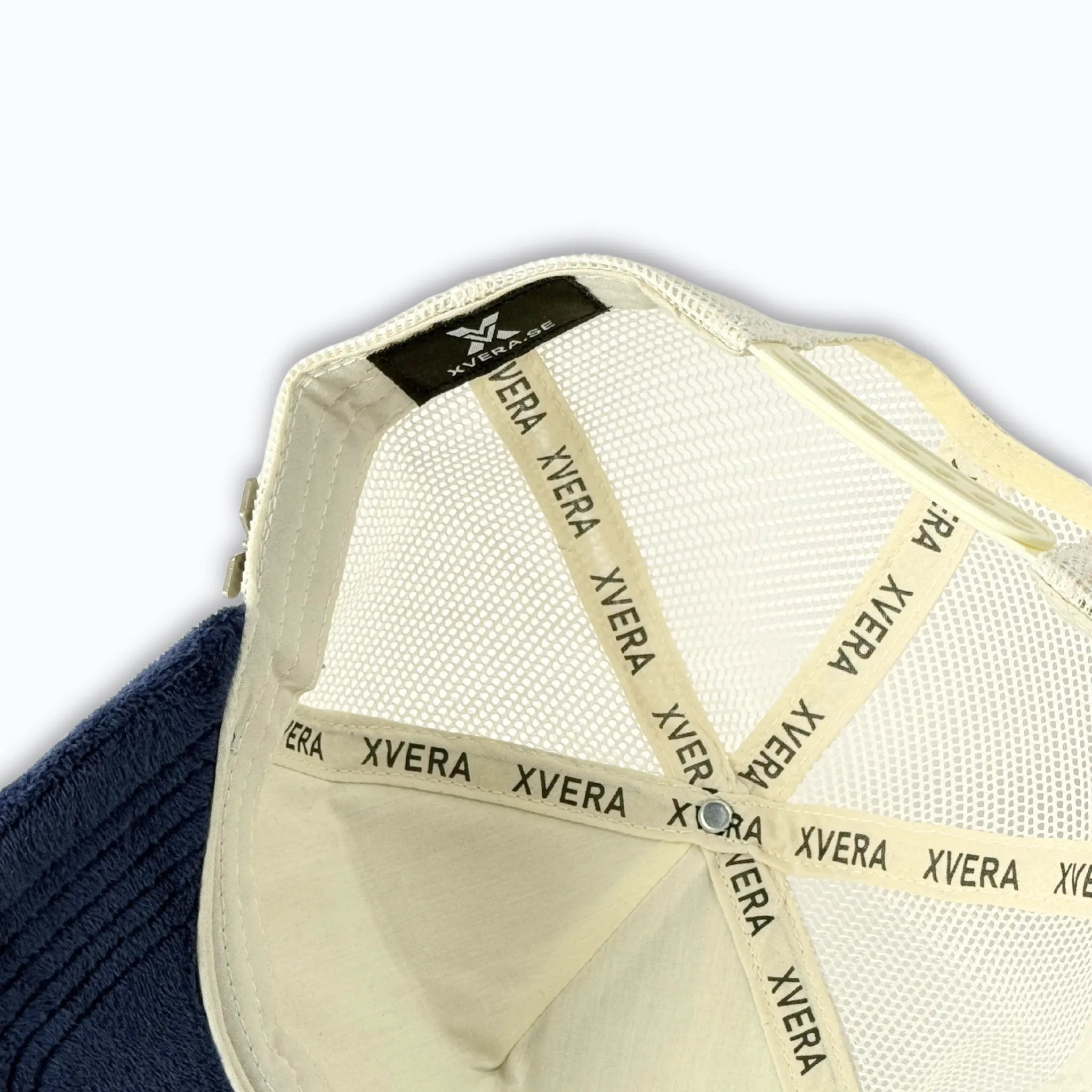 Detaljbild på insidan av XVERA velvet truckerkeps, som visar justerbart spänne, premium logoband och hög kvalitet för optimal passform.